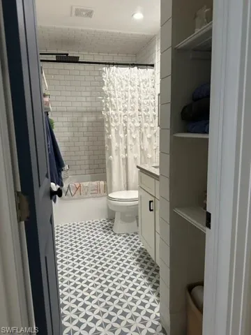 Bathroom featuring vanity, tile patterned flooring, and toilet