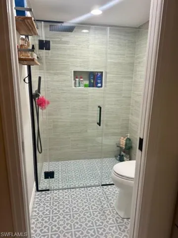 Bathroom featuring an enclosed shower, tile patterned flooring, and toilet