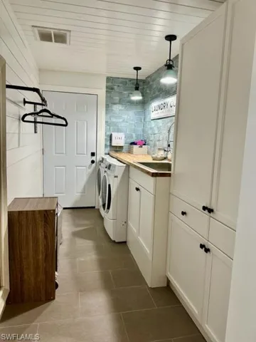 Clothes washing area featuring sink, cabinets, independent washer and dryer, and tile patterned flooring