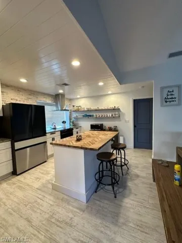 Kitchen featuring fridge, wood counters, and light hardwood / wood-style floors