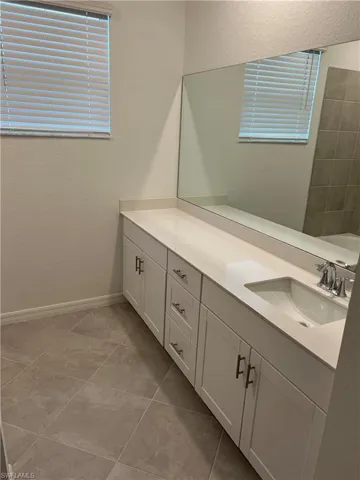 Full bath with vanity, a textured wall, and light tile patterned flooring