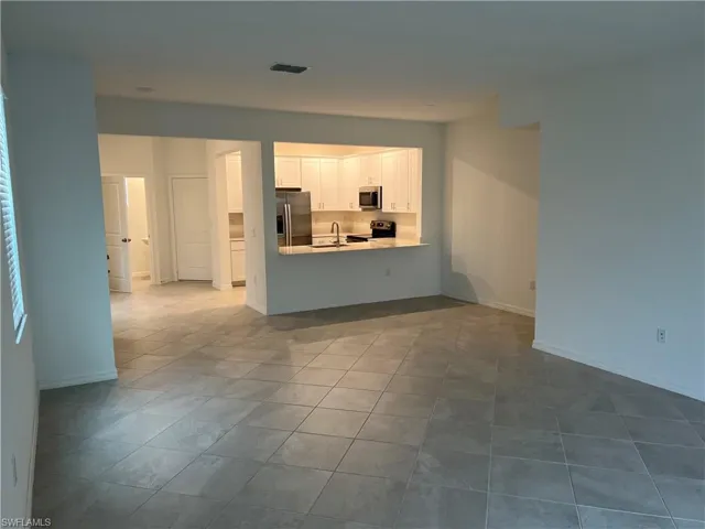 Kitchen with white cabinets, light countertops, a peninsula, appliances with stainless steel finishes, and open floor plan