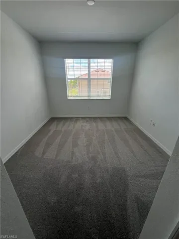 Spare room featuring light carpet and baseboards