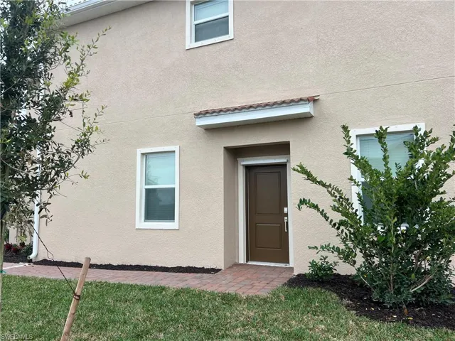 Property entrance featuring stucco siding and a yard