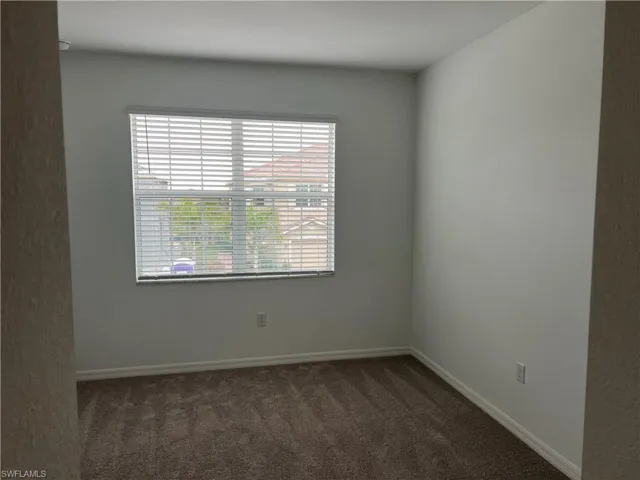 Unfurnished room with baseboards and dark carpet