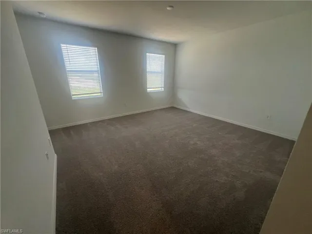 Unfurnished room featuring dark colored carpet
