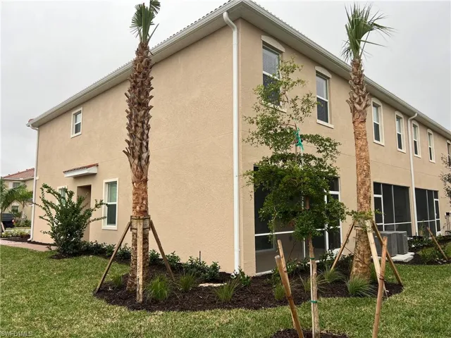 View of side of property featuring stucco siding, a lawn, and a sunroom