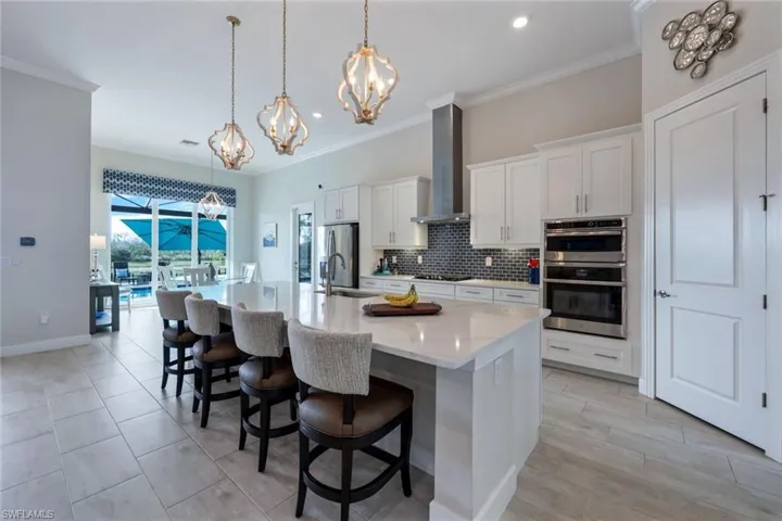 Kitchen boasts an oversize island, custom backsplash, walk-in pantry, gas cooktop, custom lighting, and stainless steel appliances.