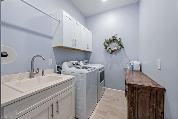 Spacious laundry room with additional cabinetry for extra storage and utility sink.
