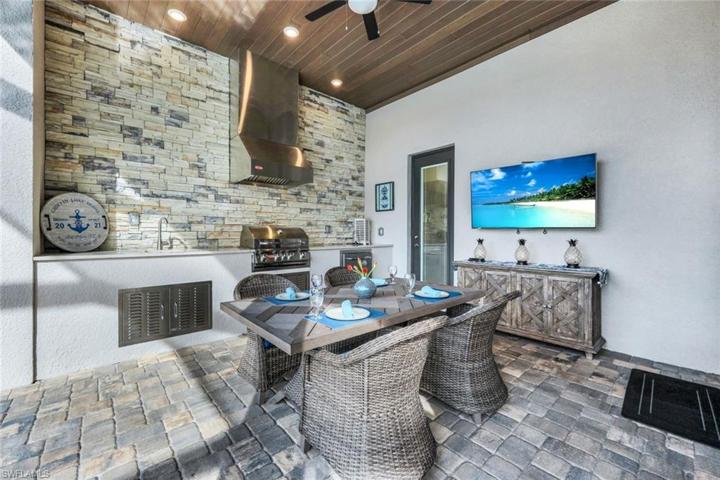 Enjoy dining outdoors with this fabulous outdoor kitchen featuring an oversize gas grill, beverage cooler, sink, and plenty of space for entertaining!