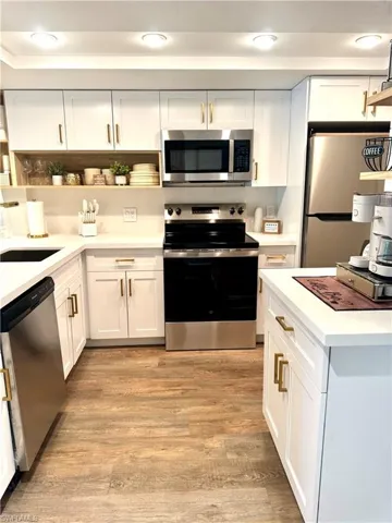 Kitchen featuring stainless steel appliances, open shelves, light countertops, and white cabinetry