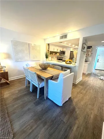 Dining area featuring dark wood-type flooring, visible vents, and baseboards