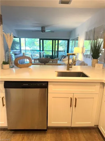 Kitchen with a sink, white cabinetry, open floor plan, light countertops, and dishwasher