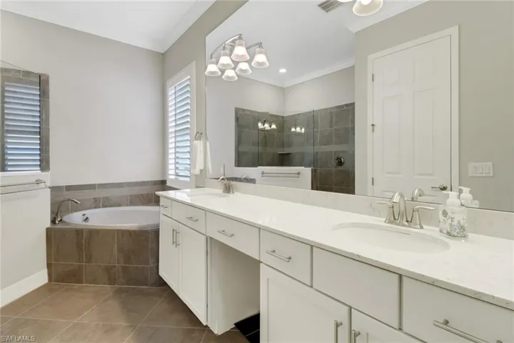 Luxurious primary bathroom featuring vanity with dual sinks, soaking tub & large tiled shower