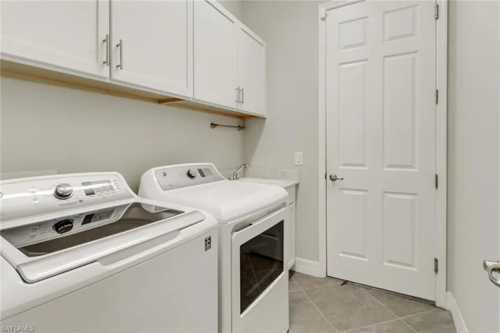 Laundry area with tile floors, cabinetry, laundry tub, washer and dryer