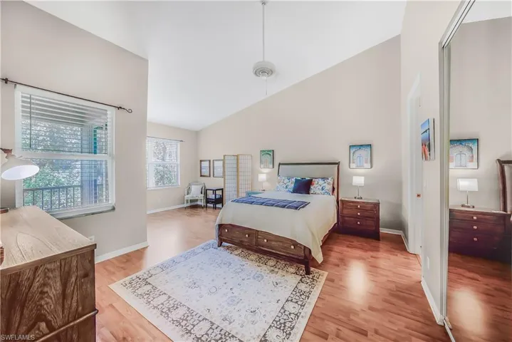 Bedroom with light wood-type flooring and high vaulted ceiling