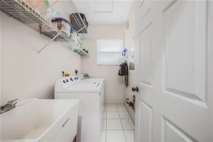 Washroom with light tile patterned flooring and washing machine and dryer