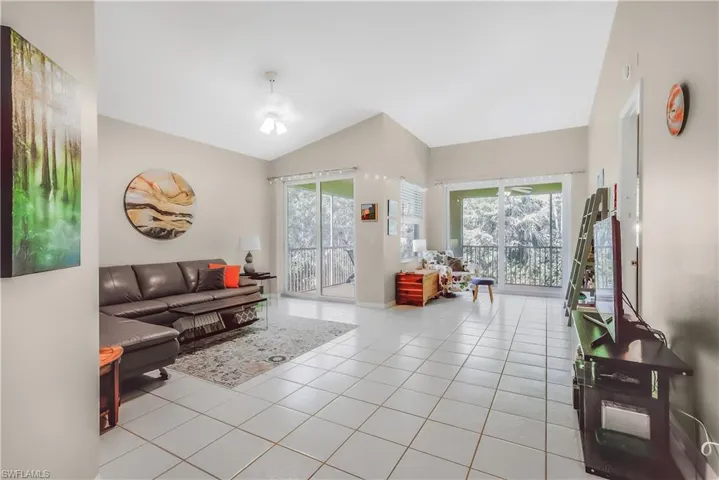 Living room featuring light tile patterned floors and lofted ceiling