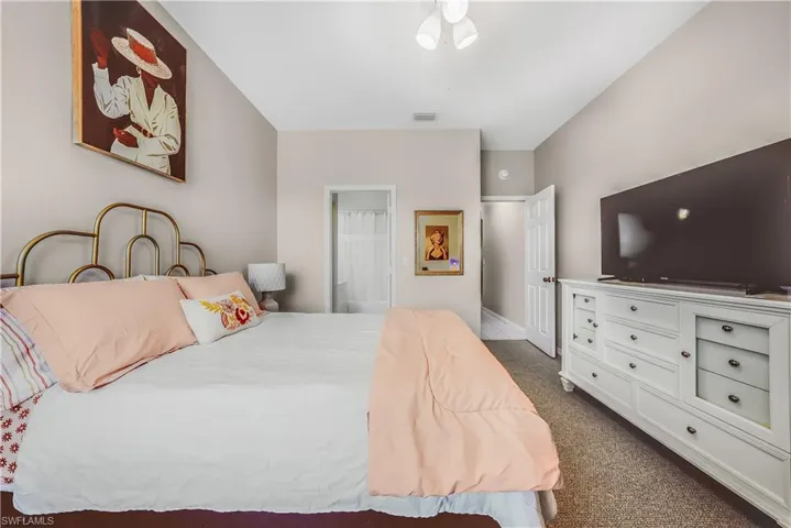Bedroom featuring dark colored carpet, ensuite bathroom, and ceiling fan