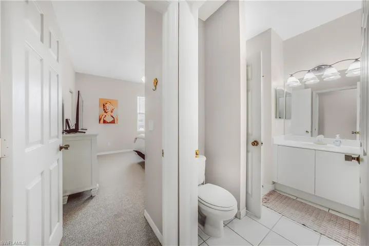 Ensuite bathroom with vanity, light carpet, and light tile patterned floors