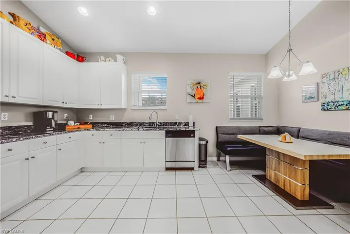 Kitchen with stainless steel dishwasher, hanging light fixtures, light tile patterned flooring, white cabinetry, and recessed lighting