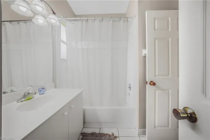 Bathroom with light tile patterned floors, vanity, and shower / tub combo with curtain
