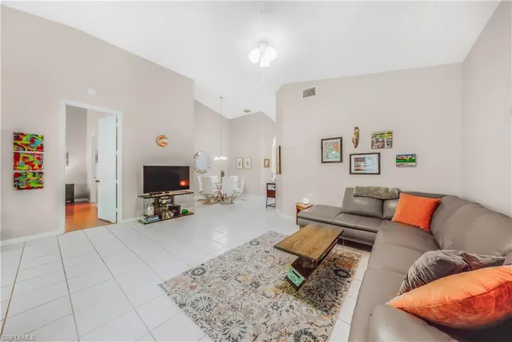 Living room with tile patterned floors, vaulted ceiling, and a ceiling fan