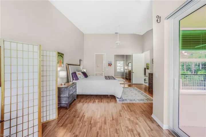 Bedroom with light wood-style floors and a towering ceiling