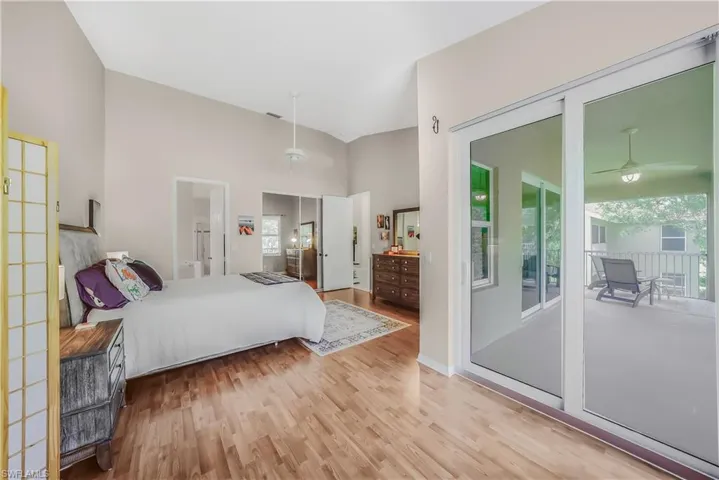 Bedroom with light wood-style floors, multiple windows, access to exterior, and a towering ceiling