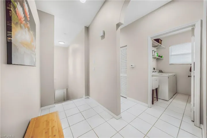 Corridor with light tile patterned floors, separate washer and dryer, and arched walkways