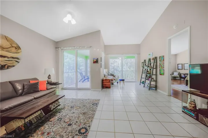 Living area with light tile patterned flooring, lofted ceiling, and ceiling fan