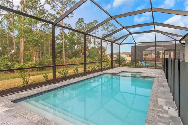 View of swimming pool with glass enclosure, a pool with connected hot tub, and a patio