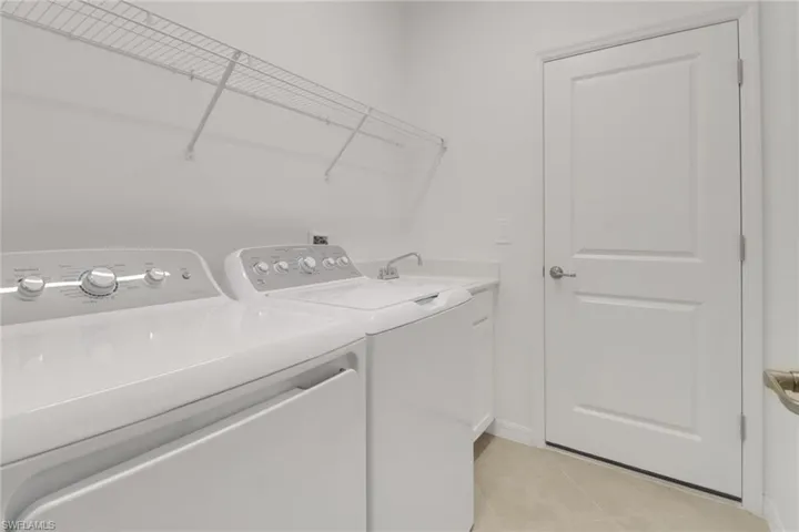 Washroom with light tile patterned floors, cabinet space, and separate washer and dryer