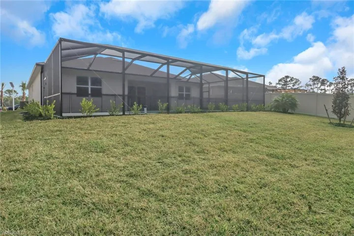 Rear view of property with a lawn, a lanai, and a fenced backyard