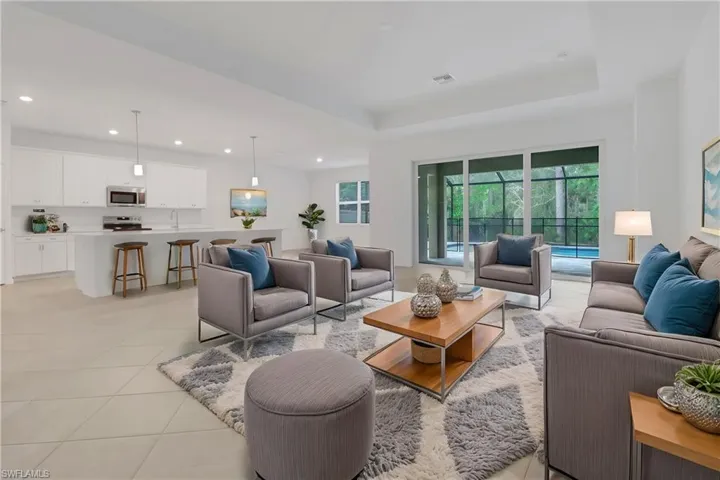 Living room with a tray ceiling, light tile patterned flooring, visible vents, and recessed lighting