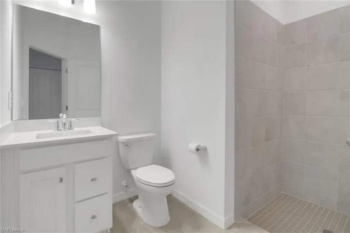 Full bathroom with baseboards, toilet, tile patterned flooring, vanity, and a shower stall