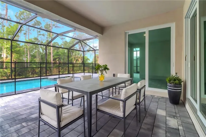 View of patio with a lanai and a pool with connected hot tub
