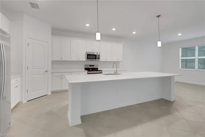 Kitchen featuring hanging light fixtures, stainless steel appliances, a sink, and light countertops