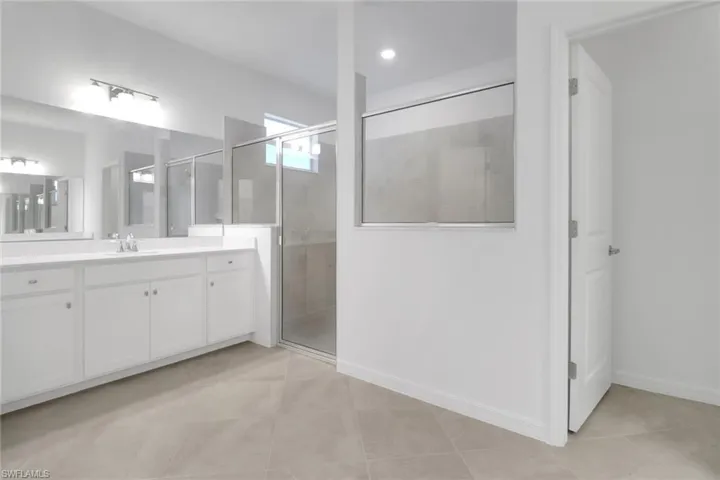 Bathroom with baseboards, a shower stall, vanity, and tile patterned floors