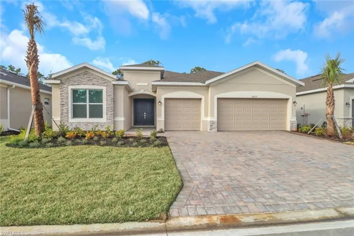 View of front of home with an attached garage, stone siding, decorative driveway, stucco siding, and a front yard