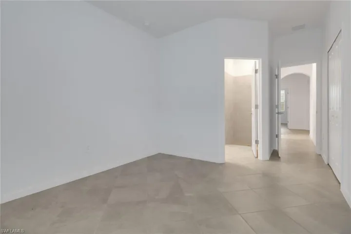 Empty room featuring arched walkways, light tile patterned floors, visible vents, and baseboards