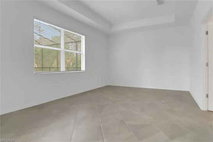 Spare room with light tile patterned floors, a raised ceiling, and baseboards