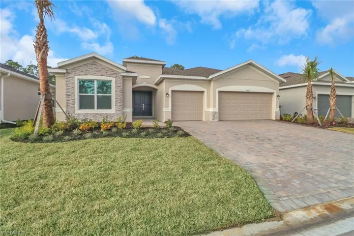 View of front of house featuring a garage, stone siding, stucco siding, decorative driveway, and a front yard
