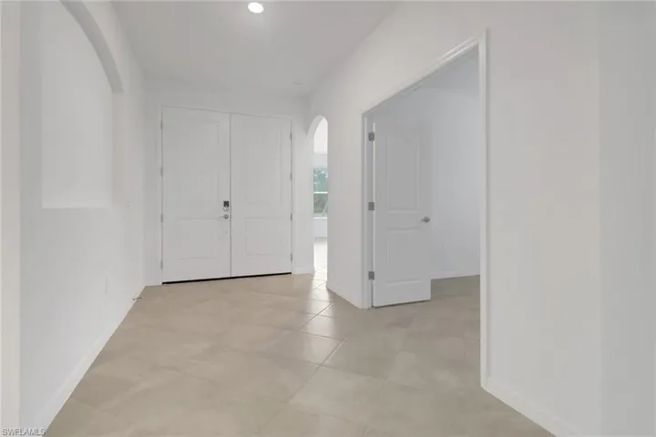 Foyer featuring arched walkways and baseboards