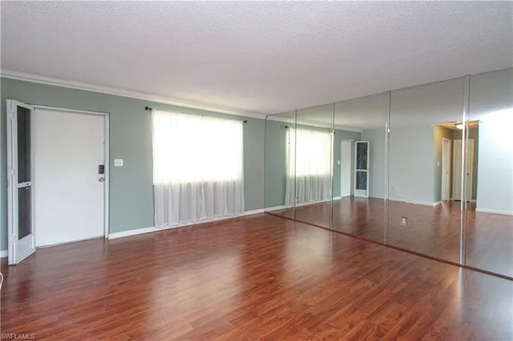 Unfurnished bedroom with dark hardwood / wood-style flooring, multiple windows, and a textured ceiling