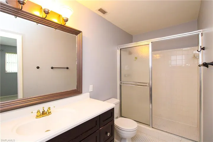 Bathroom featuring vanity, toilet, tile patterned floors, and an enclosed shower