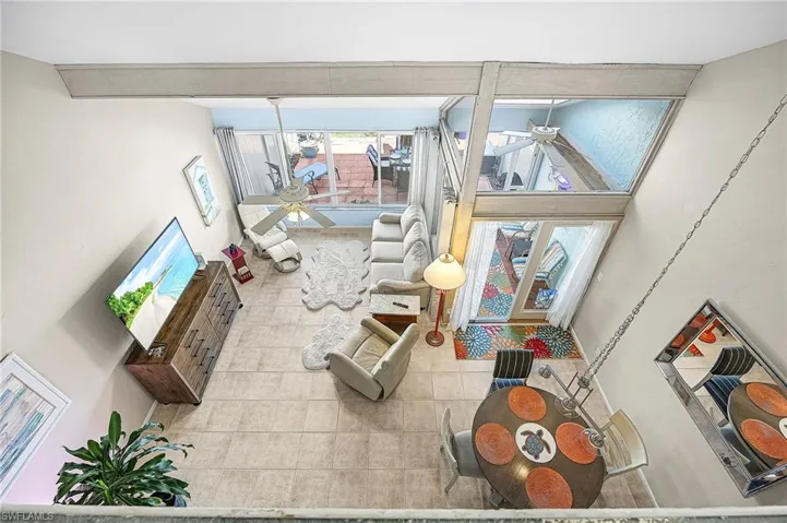 Tiled living area featuring ceiling fan and a towering ceiling