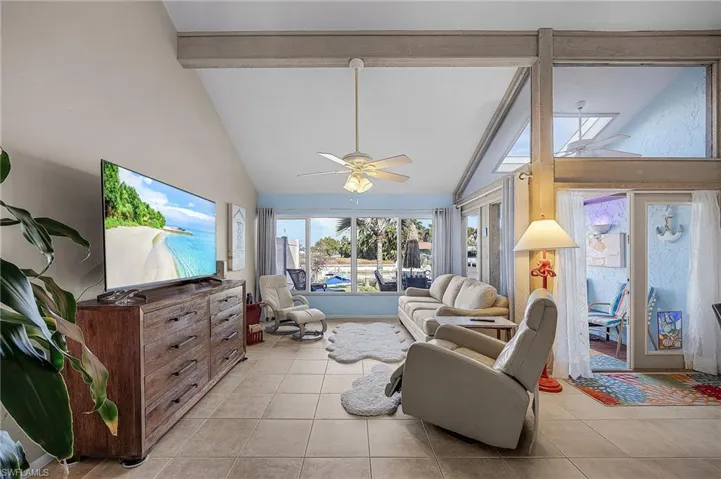 Living area with beamed ceiling, light tile patterned flooring, ceiling fan, and high vaulted ceiling
