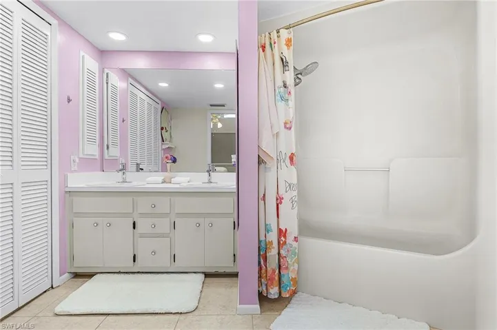 Bathroom with double vanity, light tile patterned floors, a closet, recessed lighting, and shower / bathtub combination with curtain