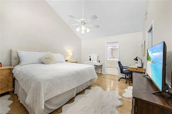 Bedroom featuring light wood-type flooring, high vaulted ceiling, ceiling fan, and a desk